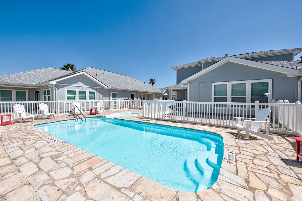 Dive into your private oasis surrounded by elegant white railings and stone decking under endless blue skies.