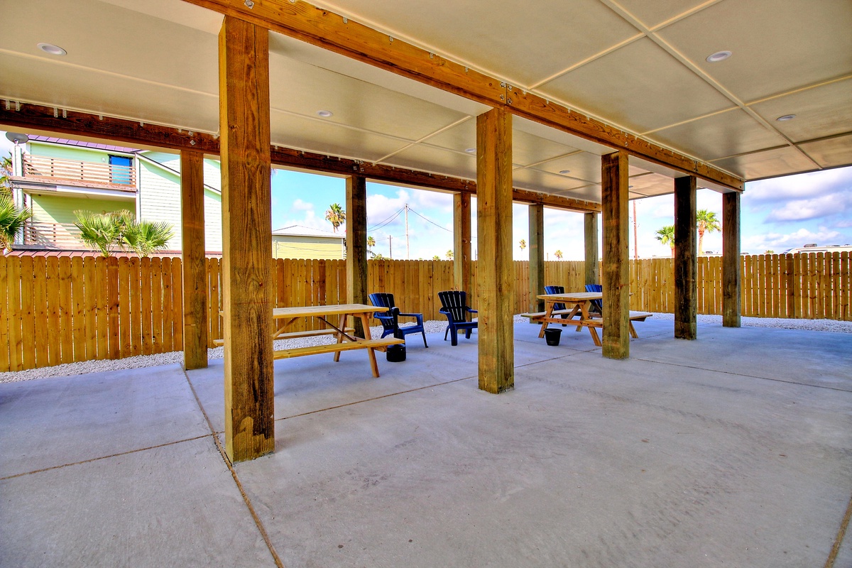 Step into your covered outdoor retreat where rustic wooden beams frame comfortable seating areas for relaxing in any weather.