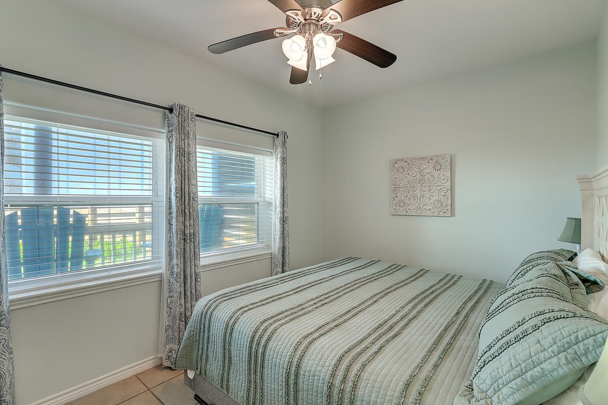 Unwind in your peaceful bedroom featuring soft linens, gentle ceiling fan, and natural light streaming through pristine windows.