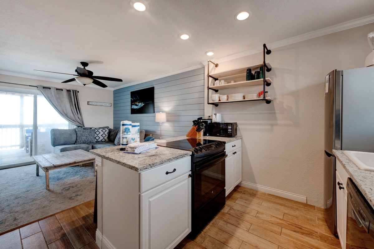 You'll love cooking in this stylish kitchen with granite counters, stainless appliances, and modern open shelving that flows seamlessly into the living area.