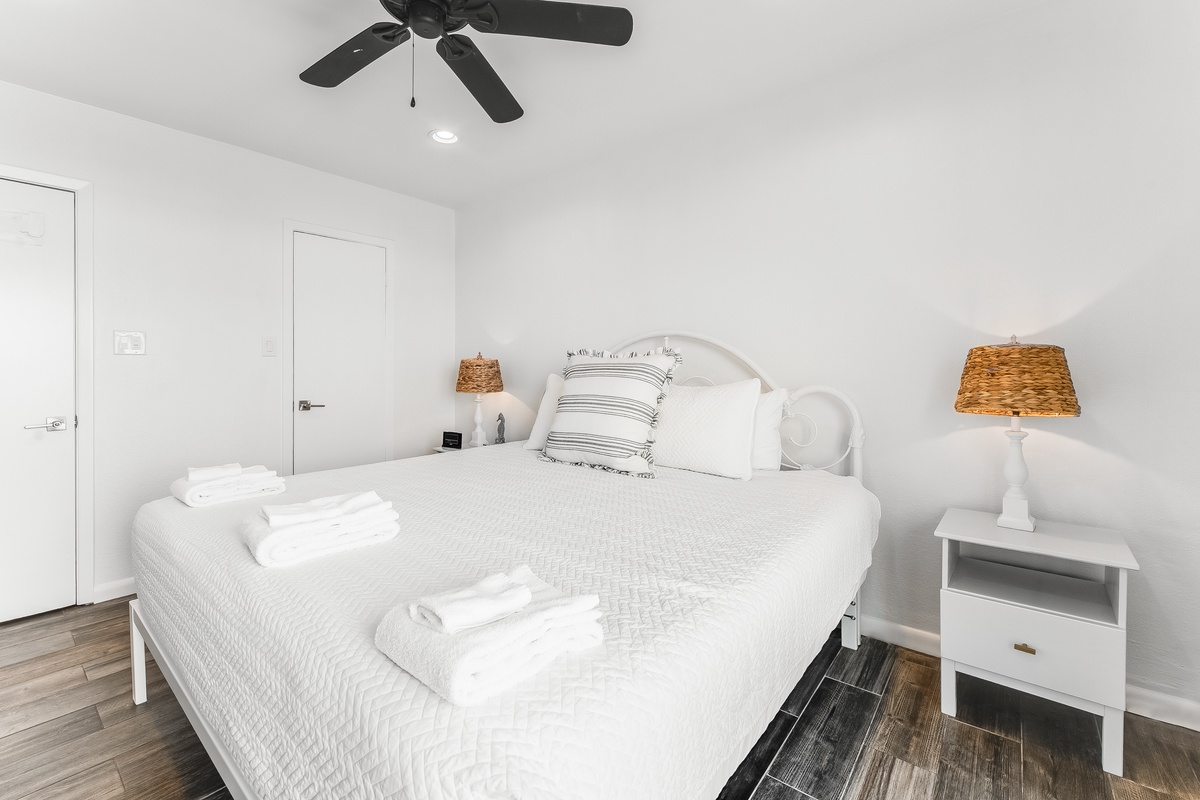 Your peaceful bedroom features crisp white linens and coastal charm with wicker accents, creating the perfect retreat for restful nights.