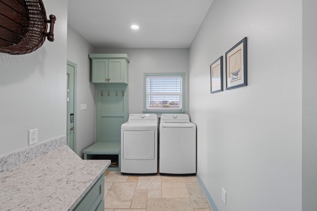 Your laundry room features a full-sized washer and dryer with charming mint green cabinetry and convenient storage hooks for easy organization.