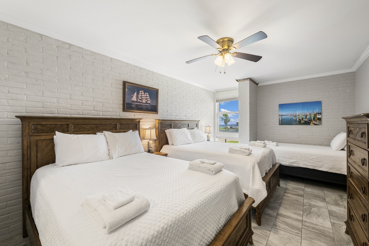 Your spacious bedroom features two comfortable beds with fresh linens, nautical artwork, and a ceiling fan for your comfort.