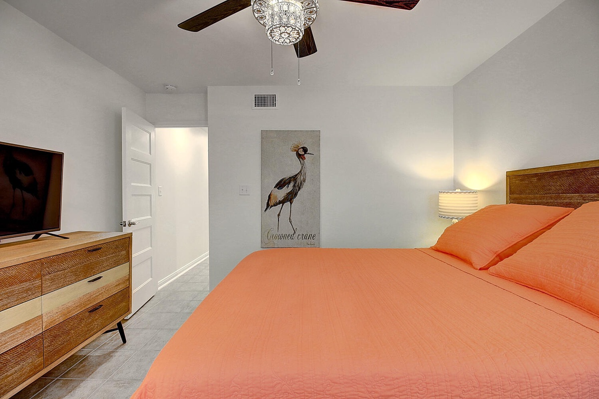 Drift off in your peaceful bedroom featuring coral bedding, elegant ceiling fan, and warm wood accents creating the perfect retreat.