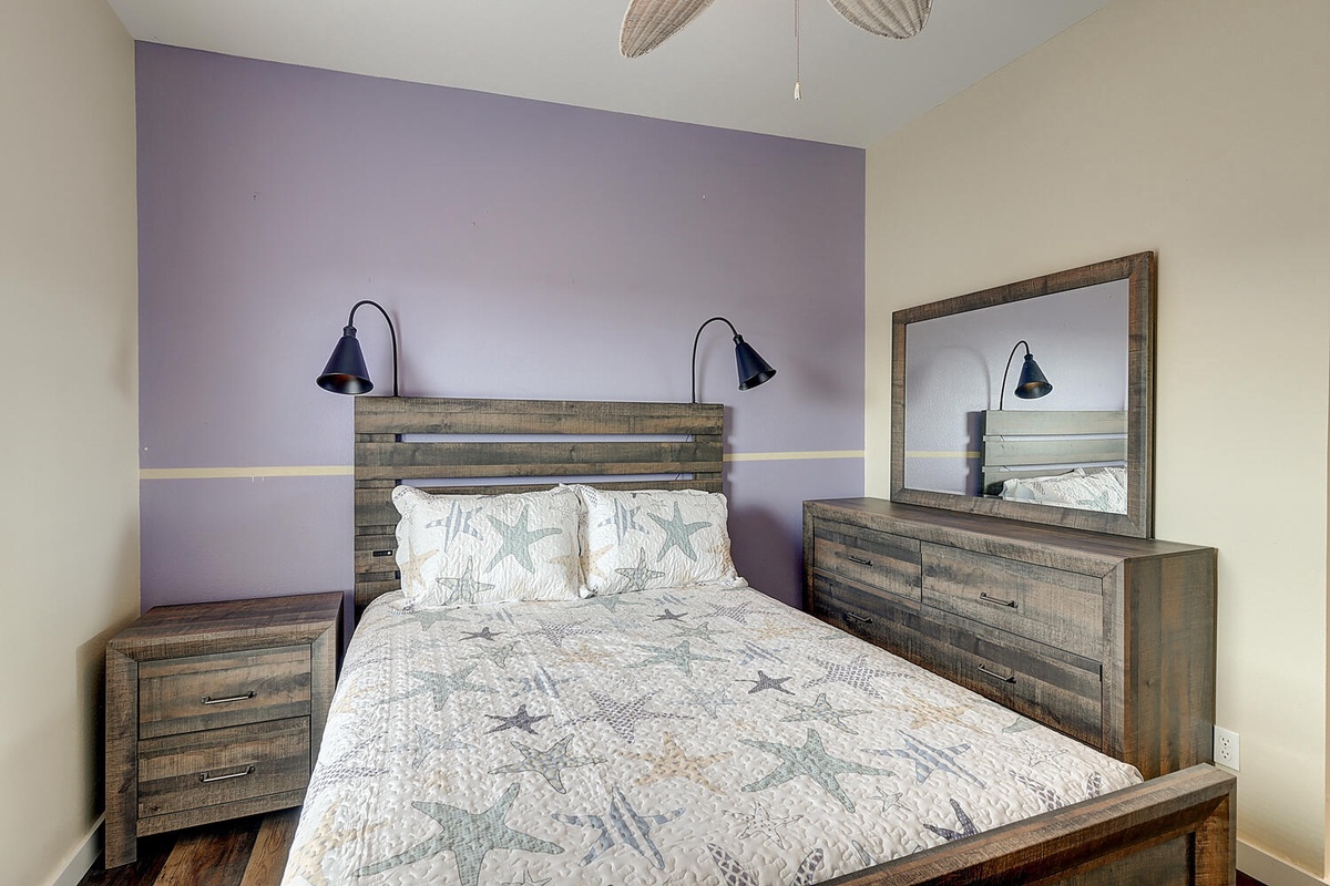 Rest easy in your cozy bedroom with rustic wood furnishings, reading lamps, and a soothing purple accent wall.
