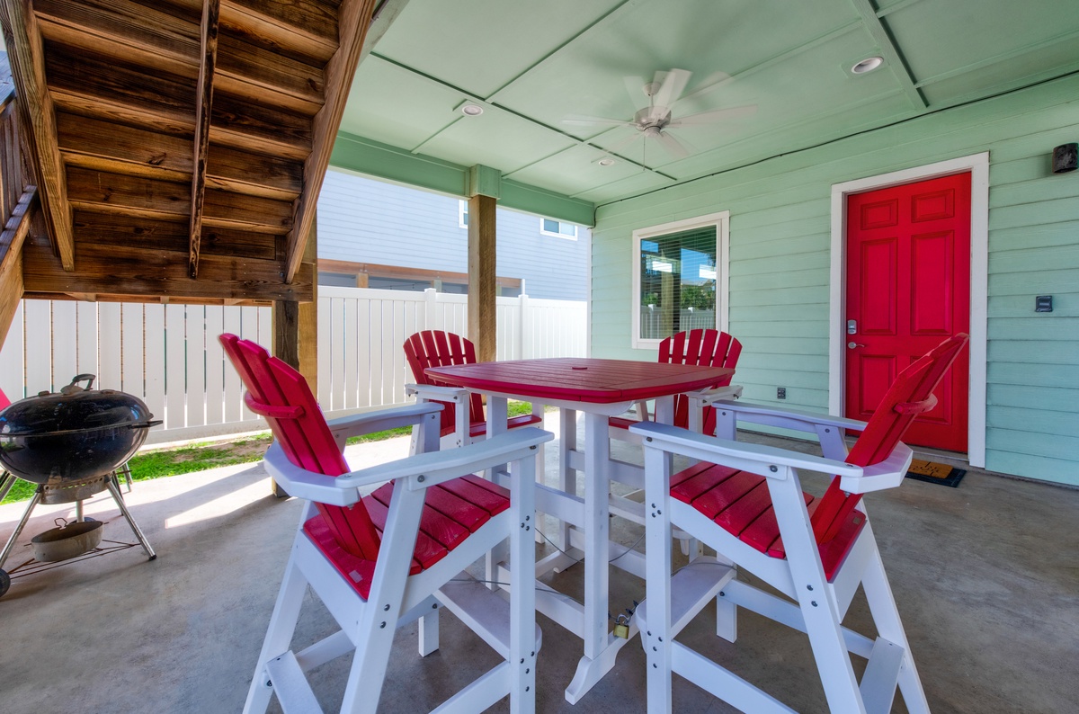 Your private covered patio invites memorable meals with vibrant red seating, ceiling fan comfort, and BBQ ready for grilling adventures.
