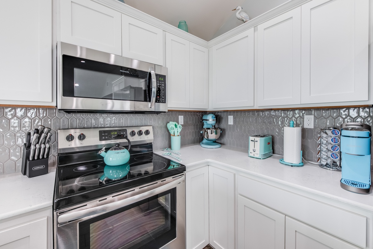 Cook your favorite meals in this bright, fully-equipped kitchen featuring modern appliances and charming turquoise accents.