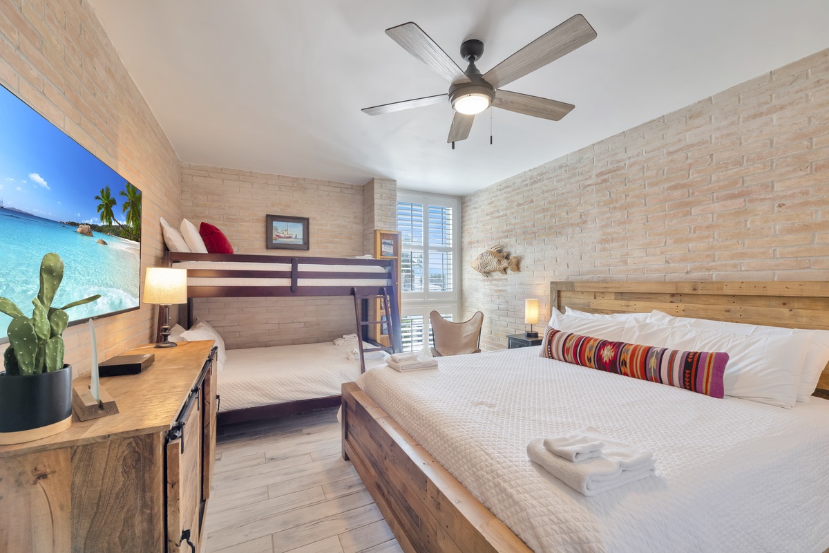 Relax in your coastal-inspired bedroom with a queen bed and bunk beds, perfect for families seeking comfort and style.