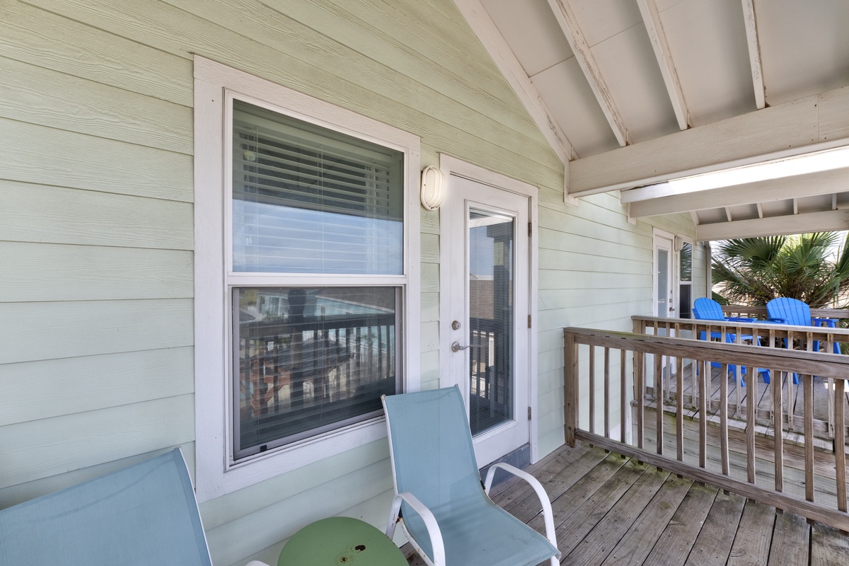 Relax on your private covered balcony with comfortable seating and peaceful beach views through tropical palms.