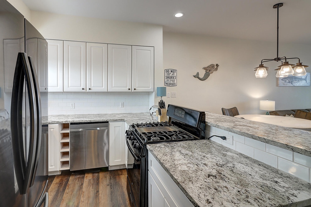 Your fully equipped kitchen features granite countertops, stainless steel appliances, and coastal charm perfect for preparing memorable meals.