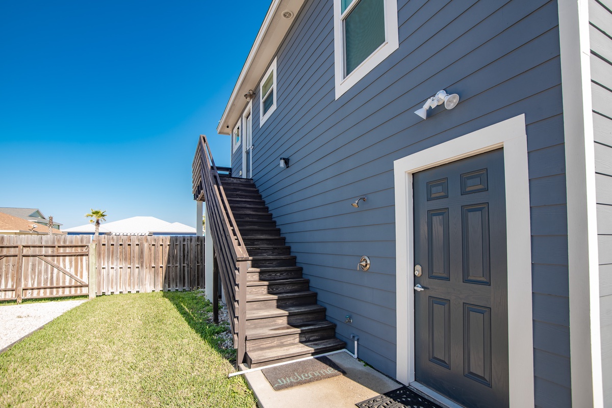 Charming coastal property featuring blue siding and inviting entrance with convenient outdoor access stairs.