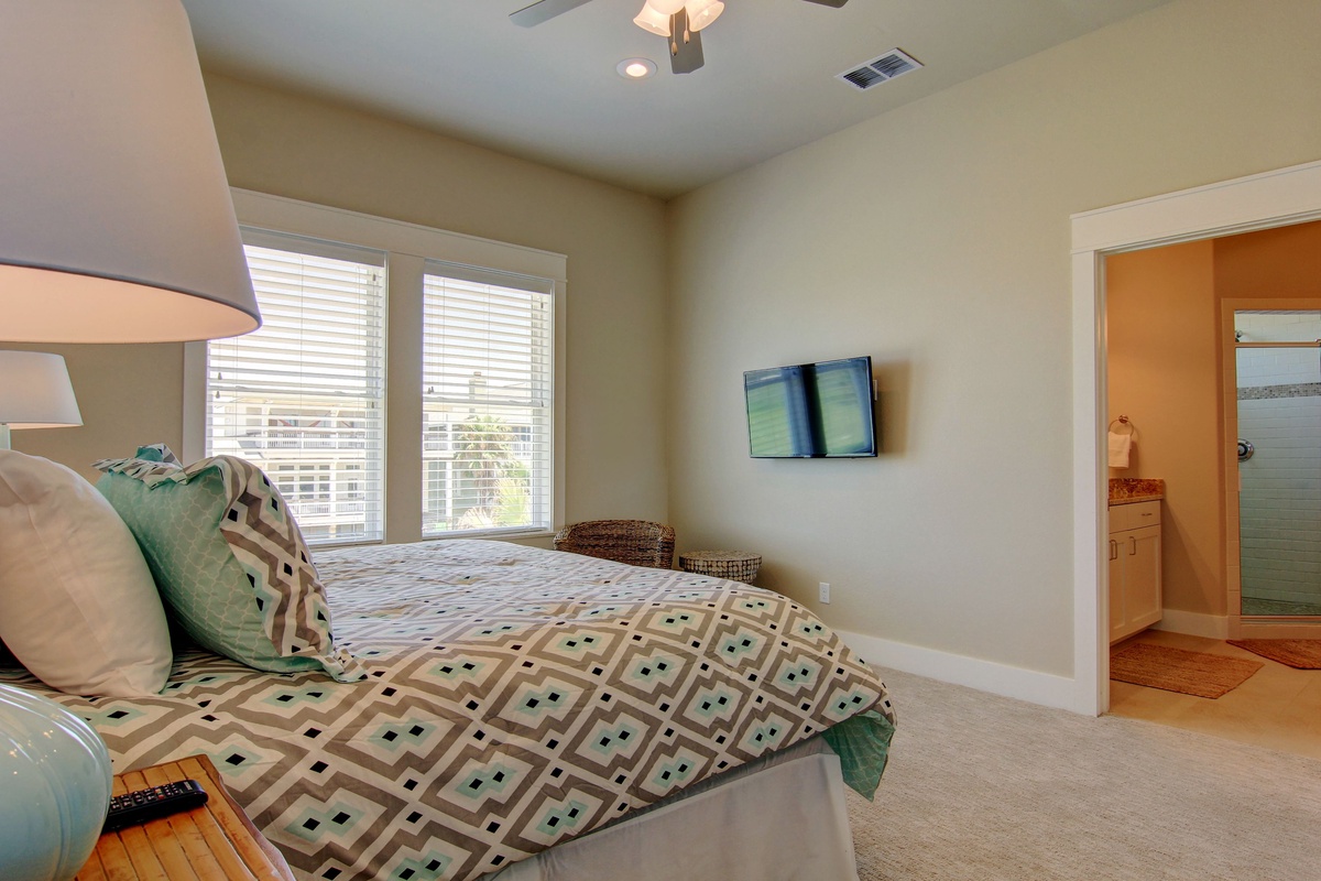 Relax in your bright bedroom with geometric bedding, wall-mounted TV, and private bathroom access for comfortable evenings.
