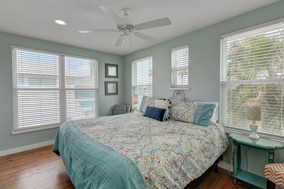 Your peaceful bedroom features soft aqua walls and natural light streaming through white blinds, creating a serene coastal retreat.