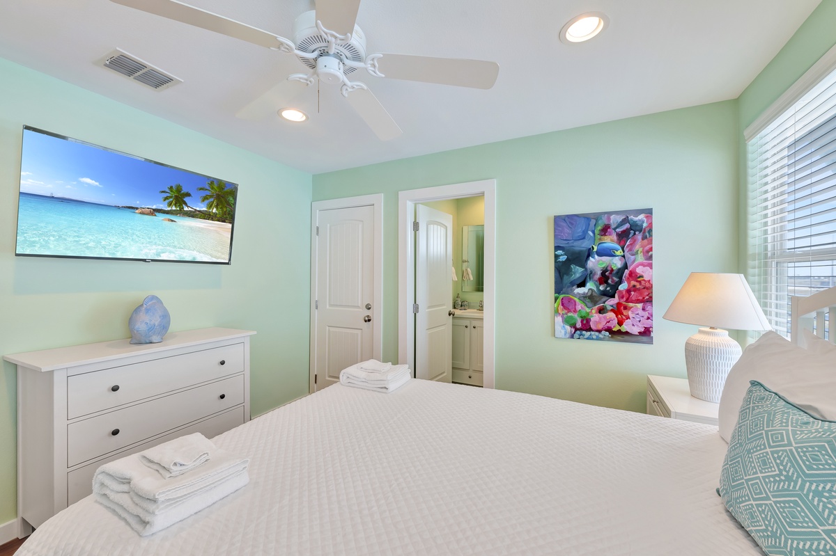 Drift into peaceful dreams in your bright, coastal bedroom with tropical artwork and ceiling fan keeping you cool.
