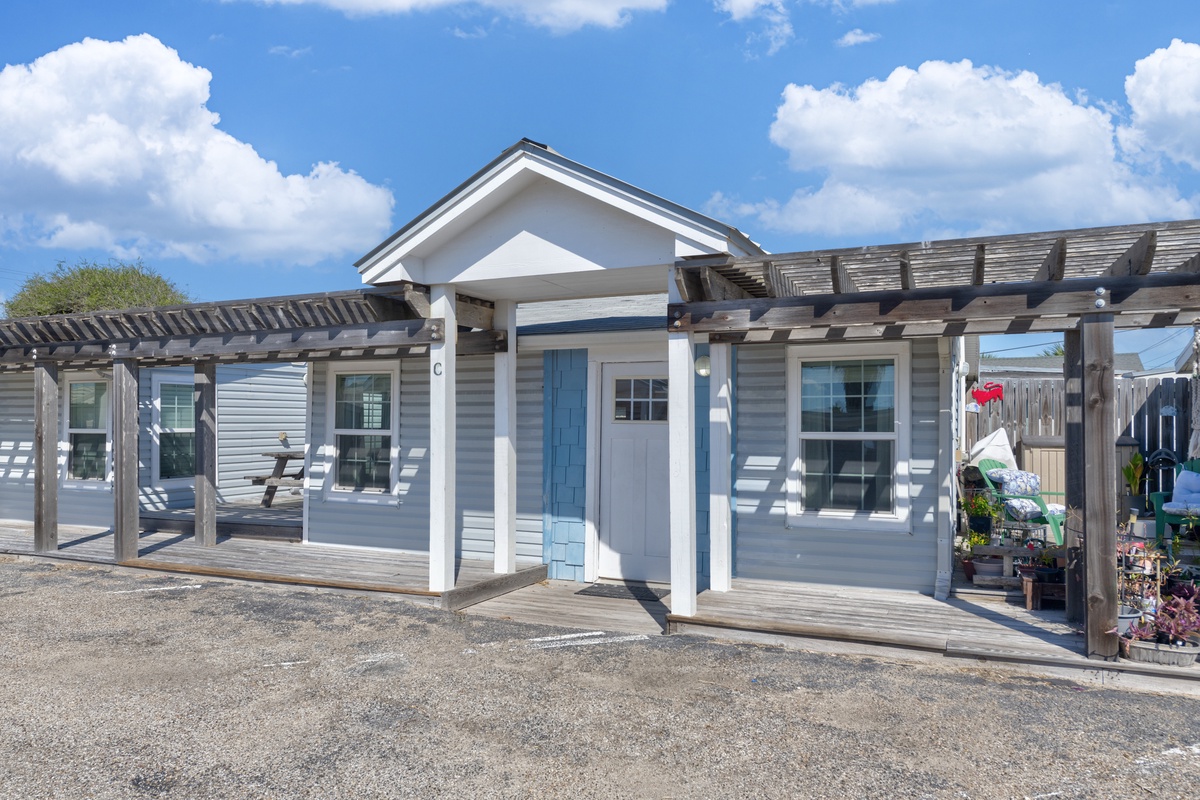 Charming coastal cottage with wraparound pergola and bright blue accents creates a welcoming beachside retreat for your getaway.