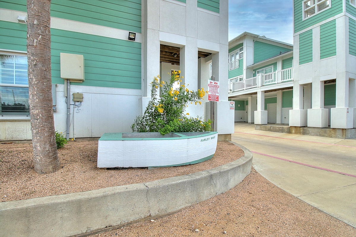 Charming beach-style property featuring distinctive turquoise and white architecture with palm trees and tropical landscaping throughout the welcoming courtyard area.