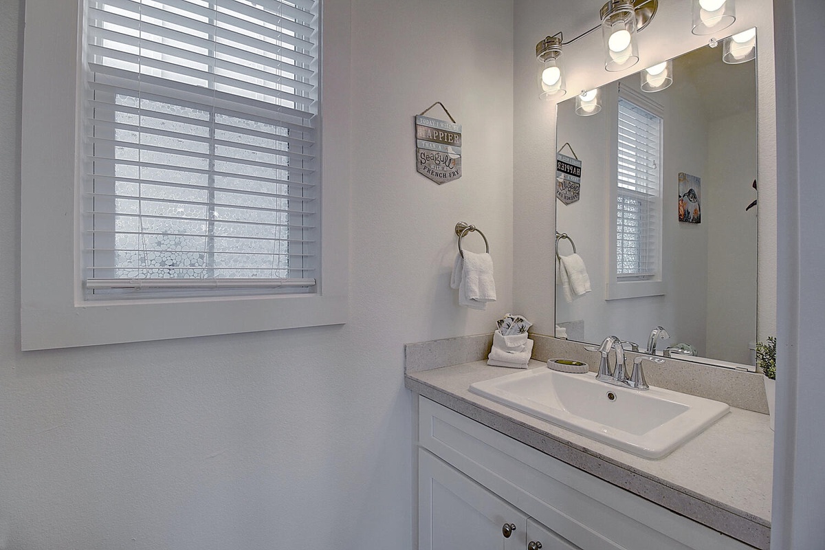 Freshen up in your bright, modern bathroom featuring granite counters, brass fixtures, and thoughtful touches like fresh towels.