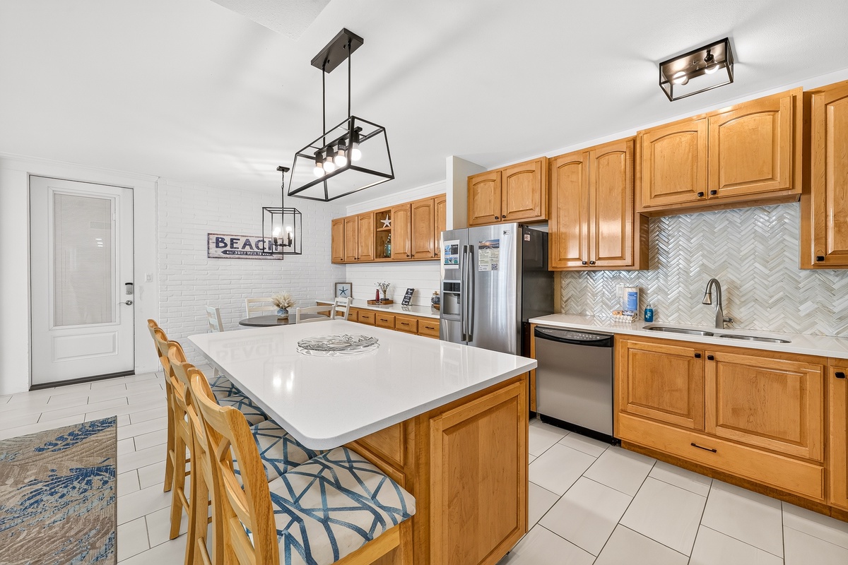 Gather around the spacious kitchen island for home-cooked meals and laughter. Warm wood cabinetry, modern appliances, and elegant tilework create an inviting space where you'll love preparing breakfast before heading to the beach.