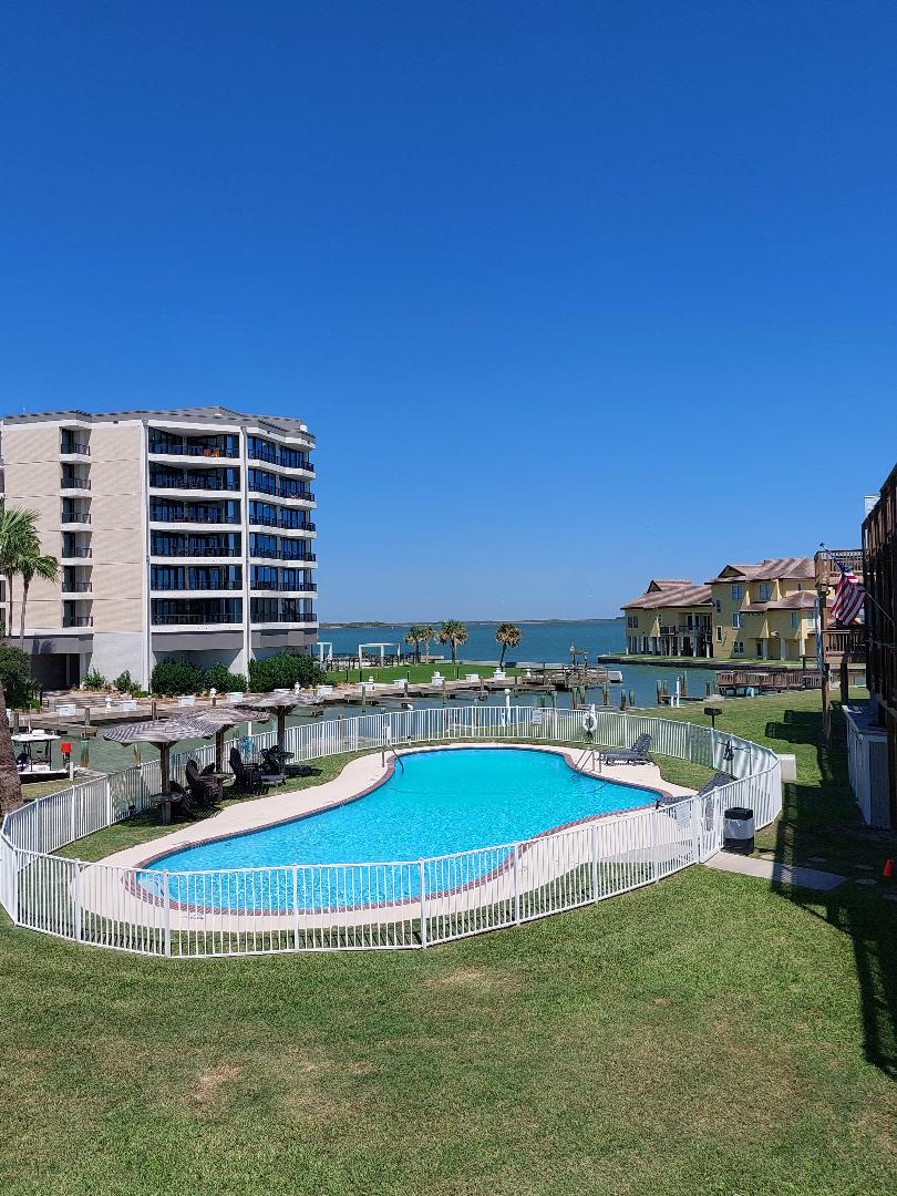 Waterfront property featuring swimming pool with bay views and nearby accommodations under clear blue skies.