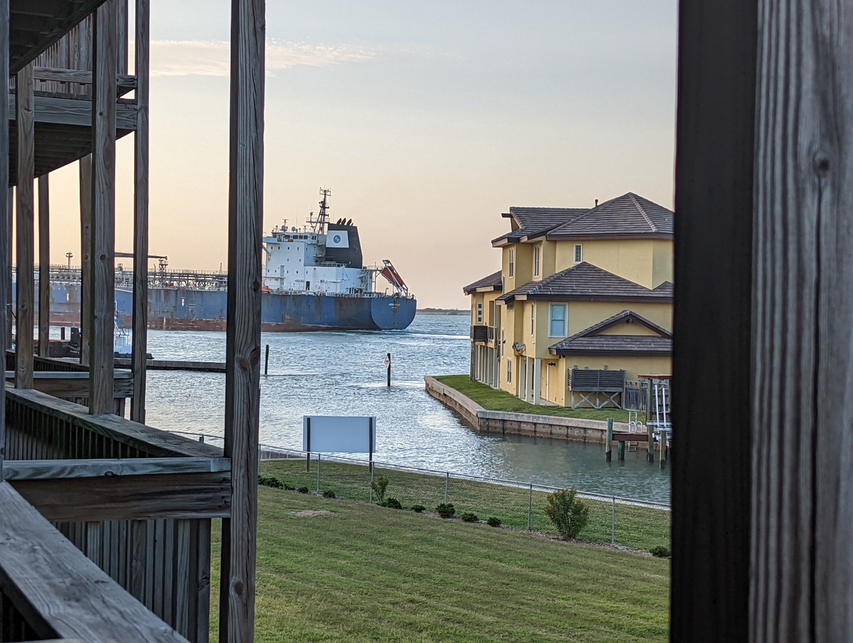 Coastal waterfront setting with harbor views, featuring waterside residential buildings and maritime activity in the surrounding area.