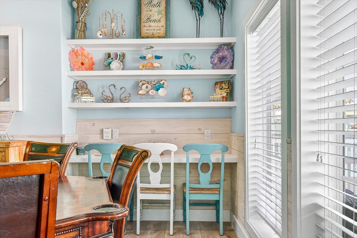 Settle into your charming breakfast nook where coastal treasures line built-in shelves above your cozy dining spot, perfect for morning coffee or planning beach adventures.