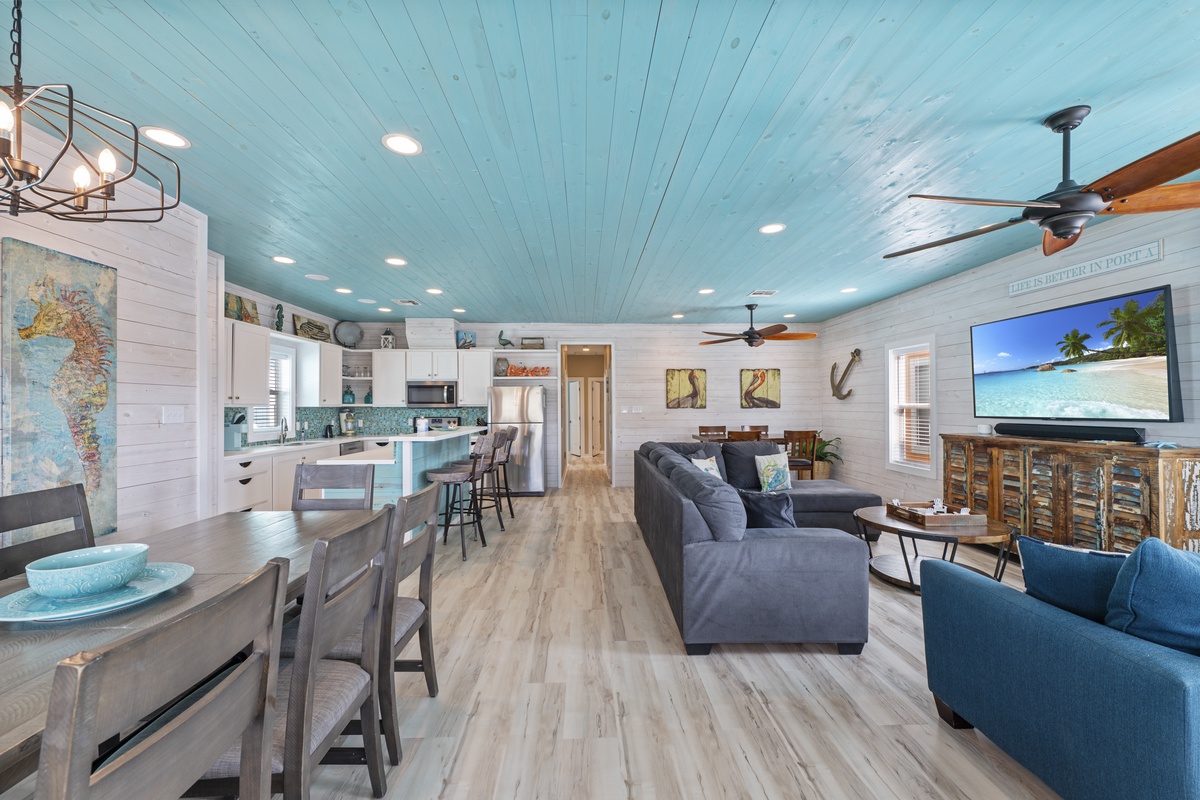 Bright and breezy coastal living awaits you in this open-concept space where turquoise ceiling beams meet beach-inspired décor. Relax in your living area, gather around the dining table, or whip up meals in the fully equipped kitchen.