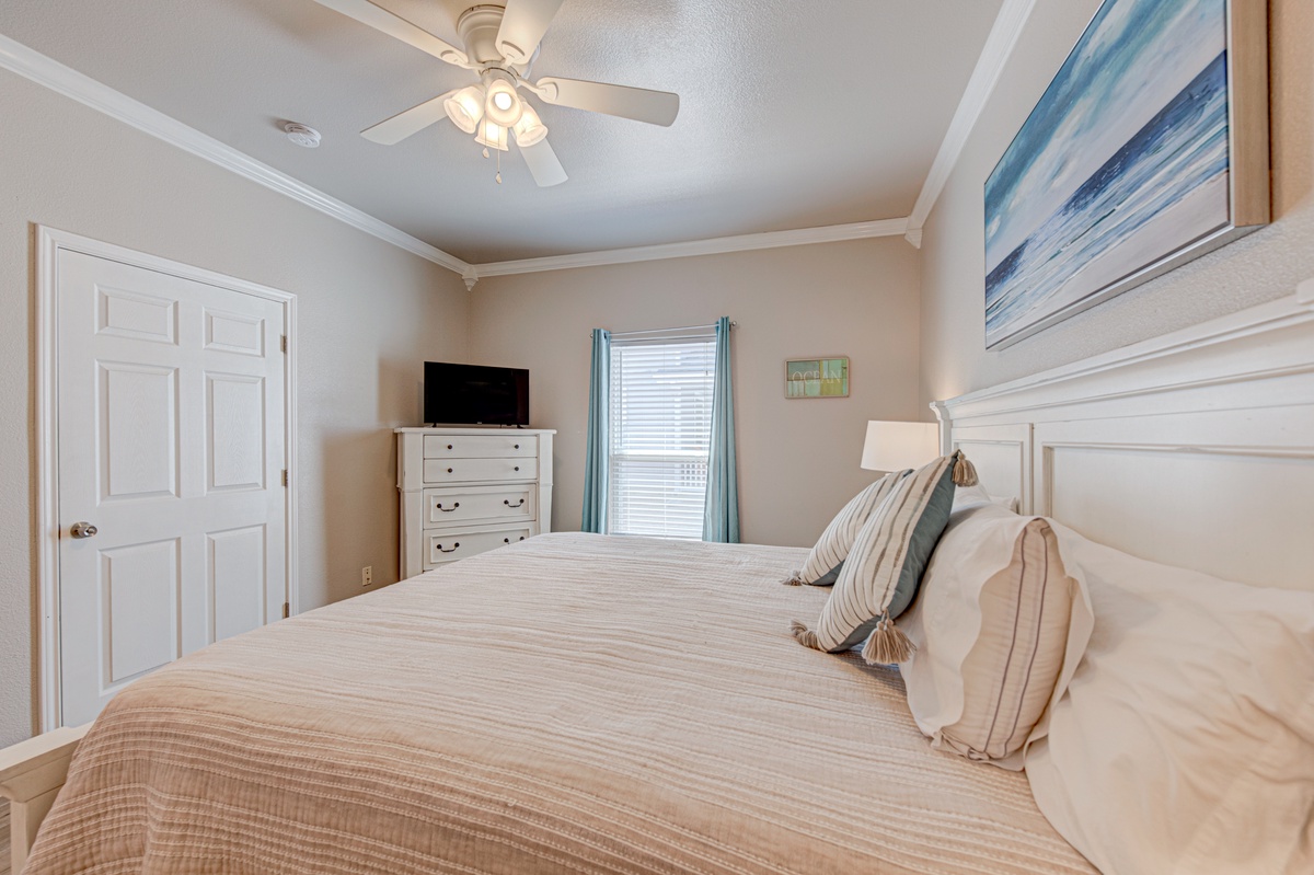 Drift off in your peaceful bedroom retreat with coastal-inspired artwork and gentle ceiling fan creating the perfect sleeping sanctuary.