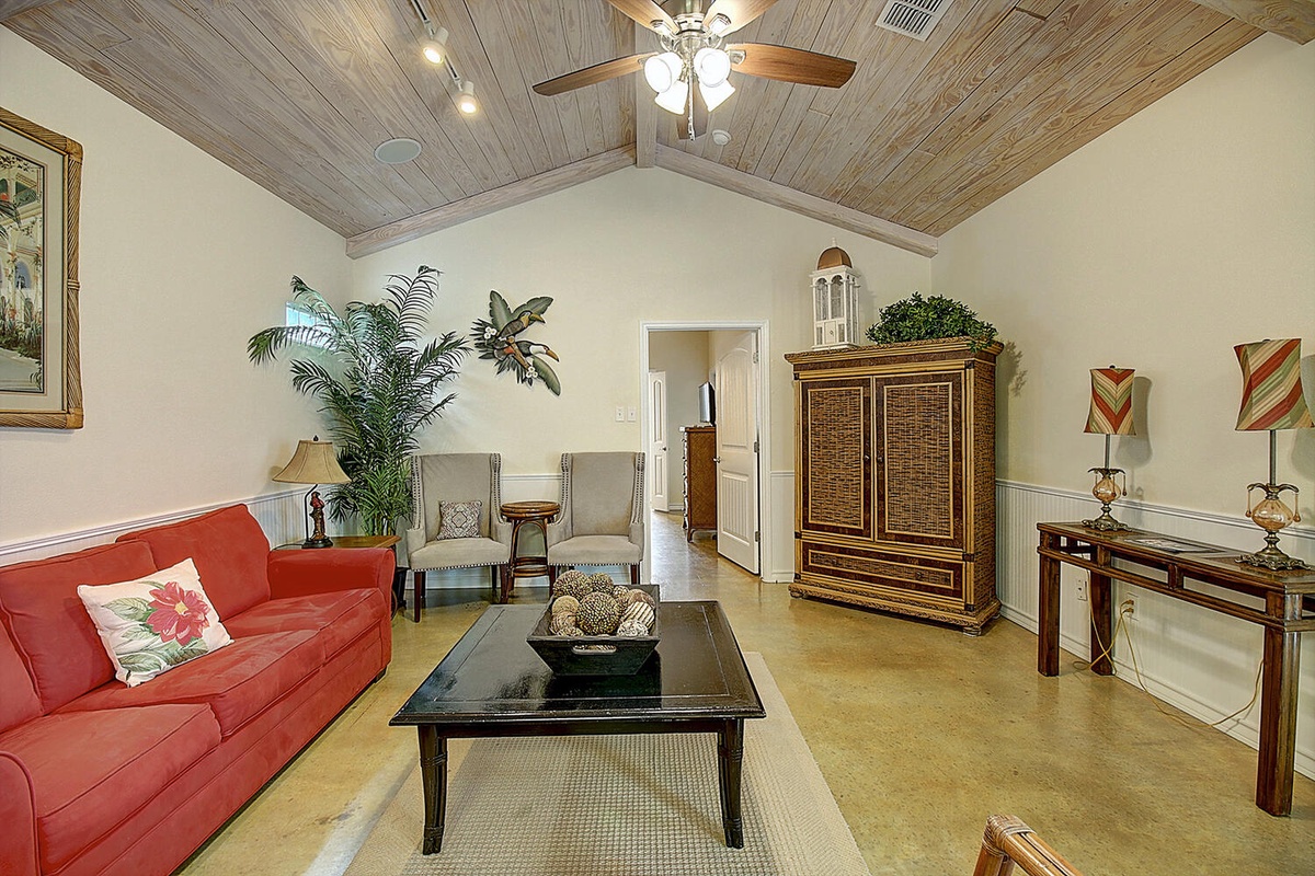 Relax in your charming living room with soaring wood-beam ceilings, comfortable seating, and tropical touches that create a warm, welcoming atmosphere.