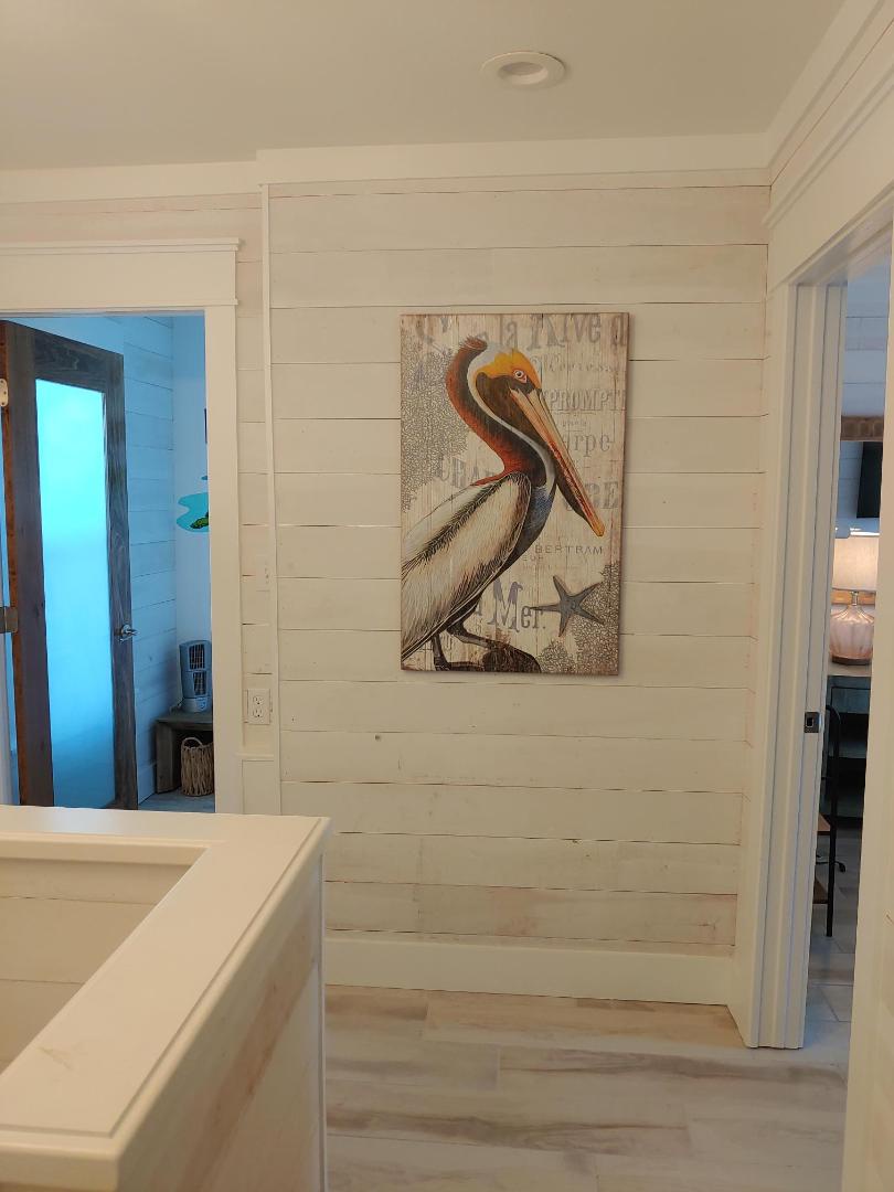 Charming coastal touches welcome you with nautical artwork adorning whitewashed shiplap walls in your bright, airy hallway.