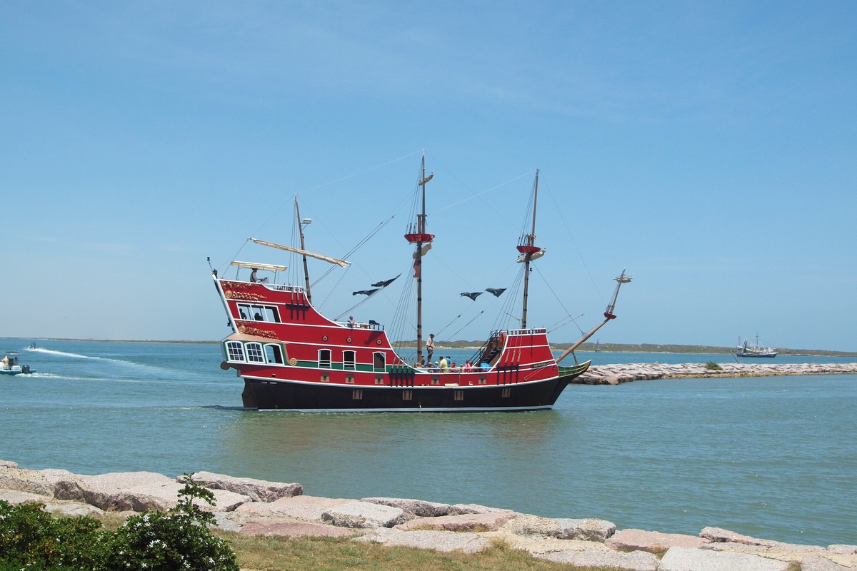 A historic pirate ship replica sails the turquoise waters near the property, adding maritime charm to the coastal location.