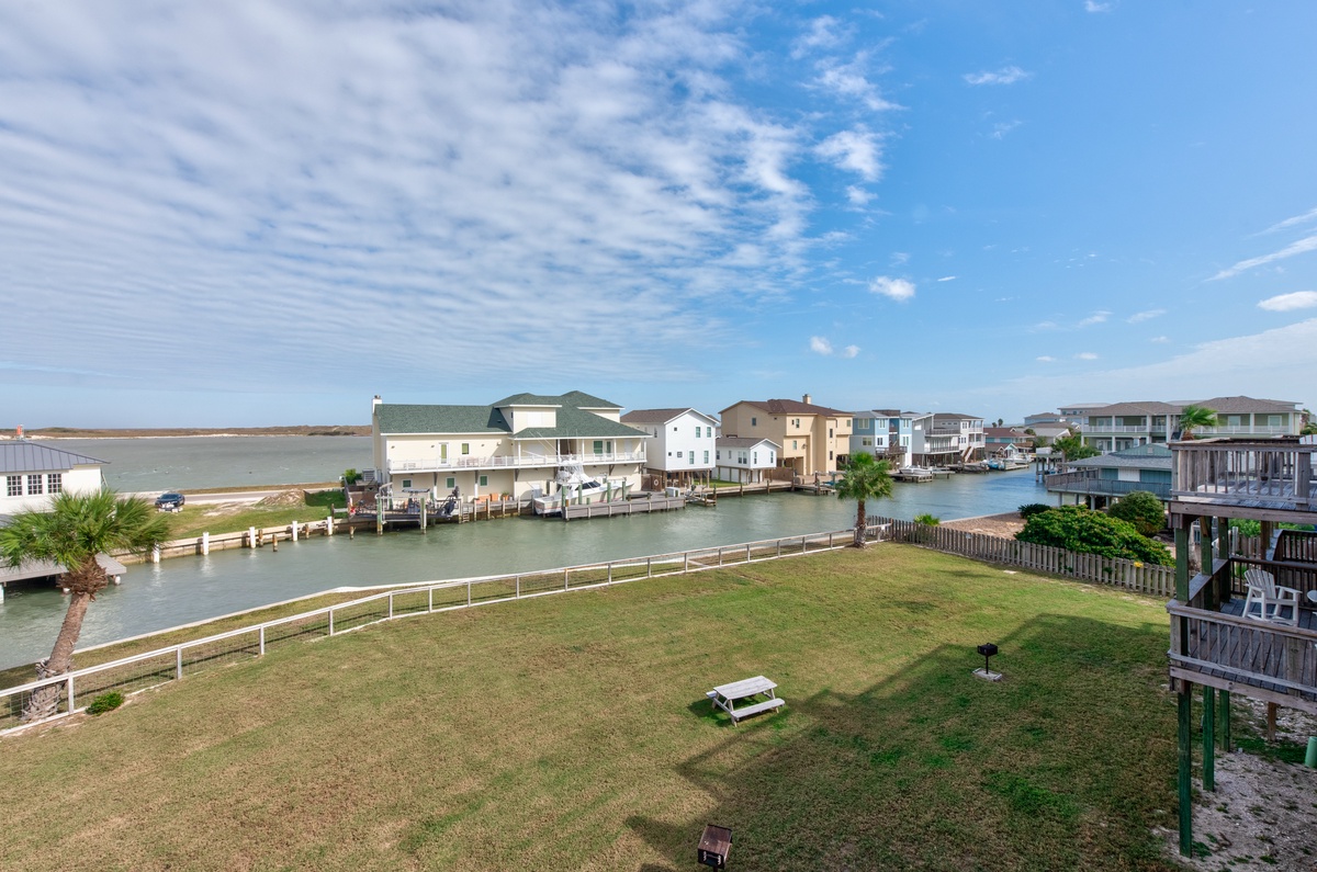 Waterfront community with canal access, boat docks, and open green space under expansive blue skies.