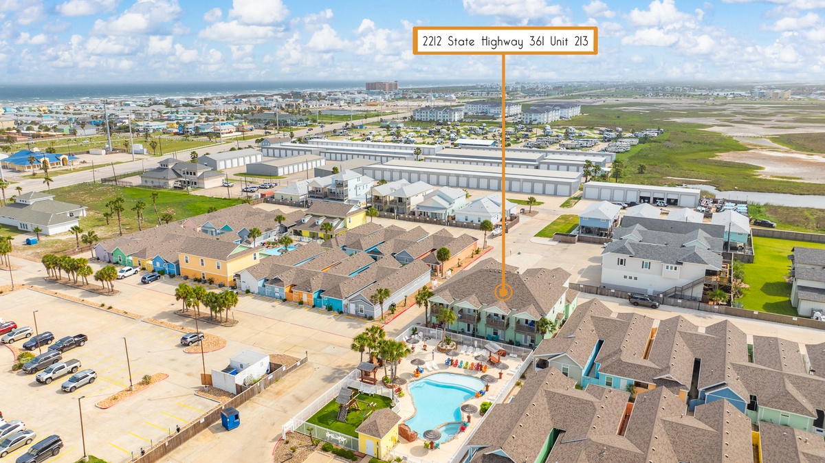 Aerial view of beachside vacation rental complex with swimming pool, colorful units, and coastal location near Port Aransas.