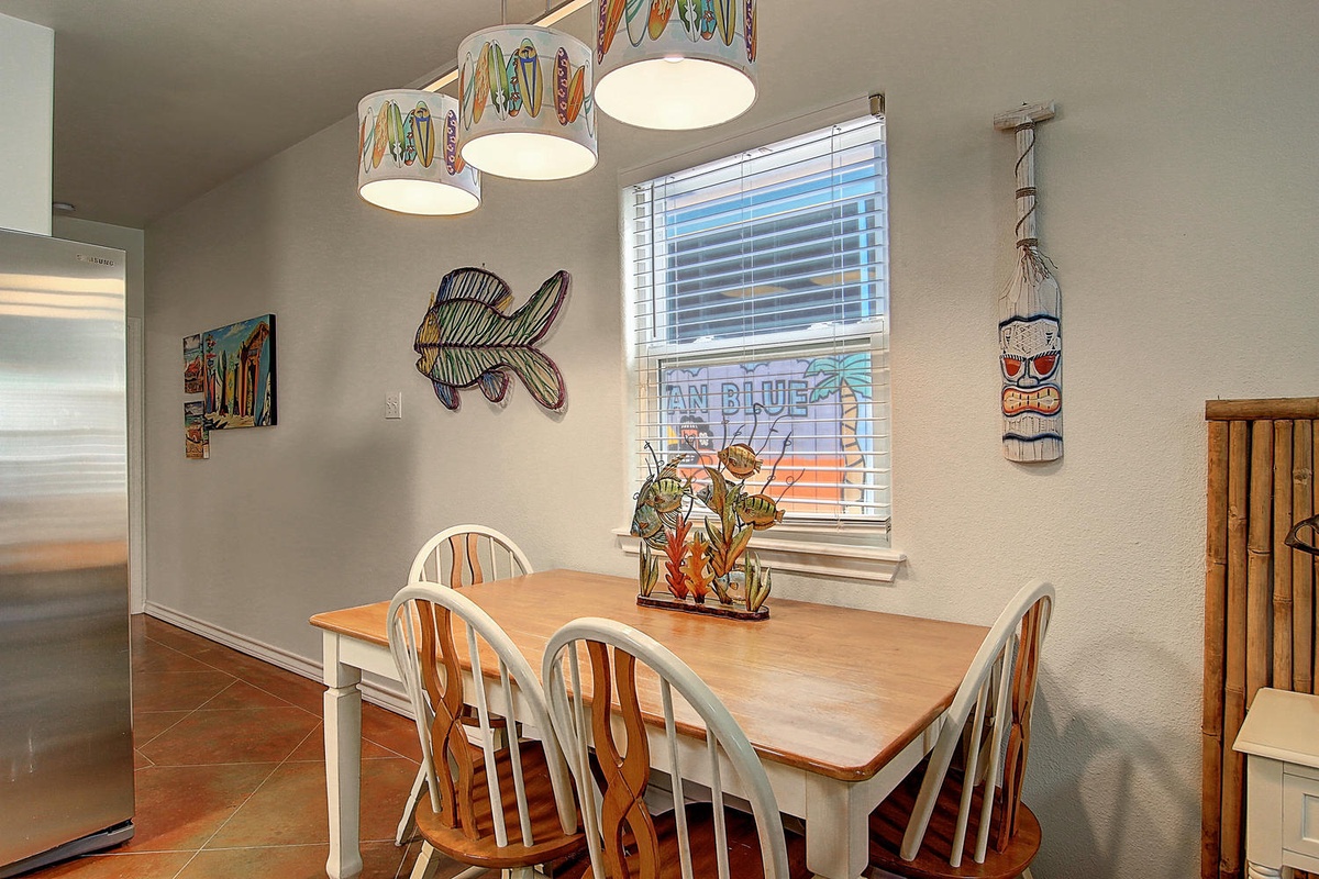 Your coastal-themed dining space features surfboard pendant lights and ocean-inspired art, perfect for enjoying morning coffee or family meals.