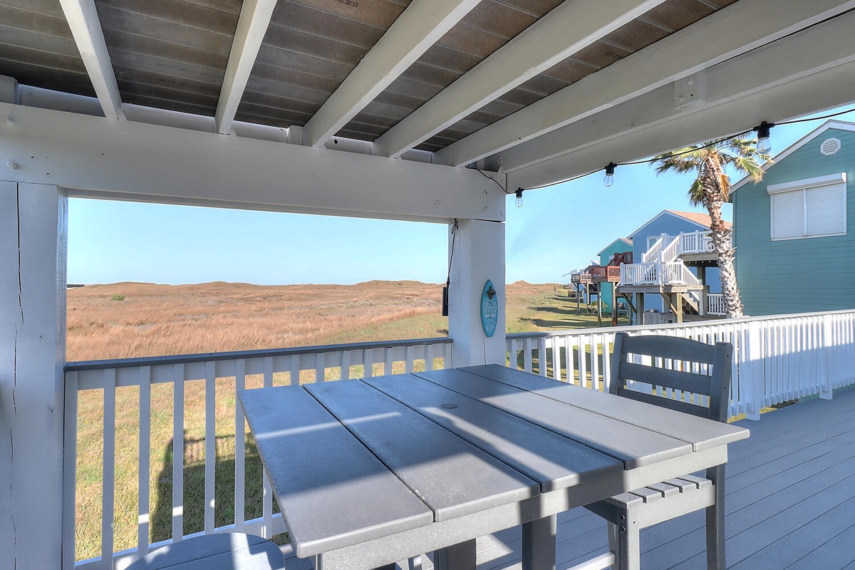 Savor your morning coffee at this covered deck table while taking in sweeping views of golden marshlands and nearby beach houses.
