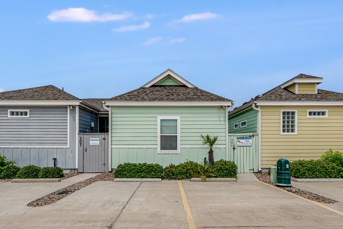Charming coastal cottages with colorful siding and dedicated parking spaces create a welcoming beachside retreat atmosphere.