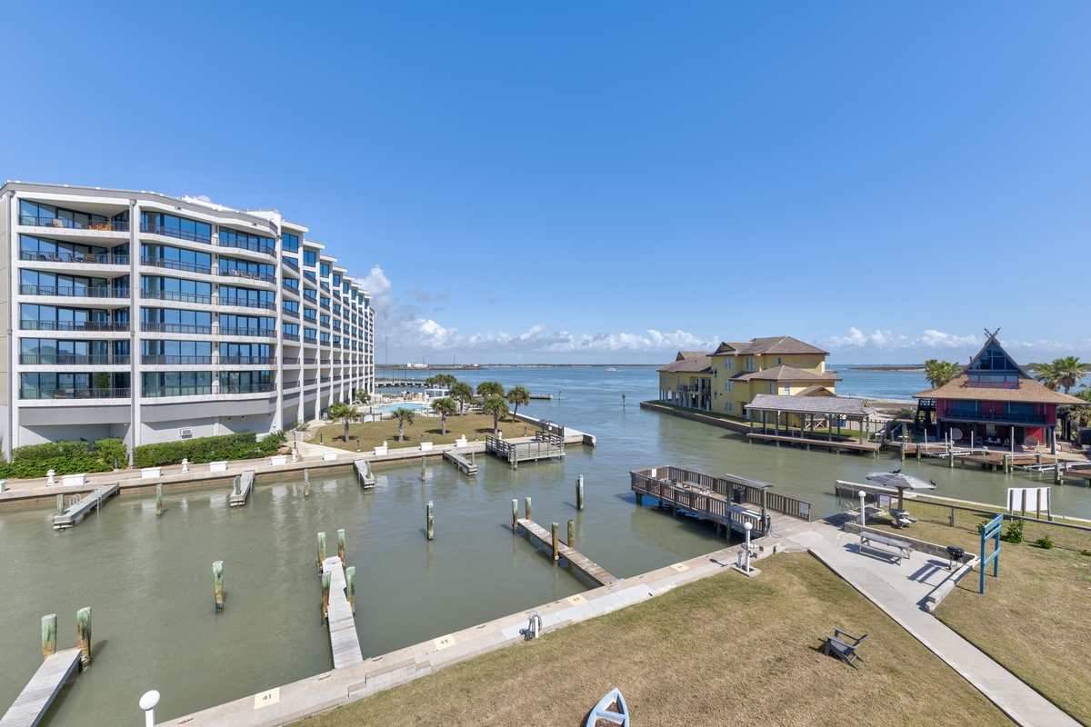 Modern waterfront property overlooking a scenic marina with boat docks and bay views under clear blue skies.
