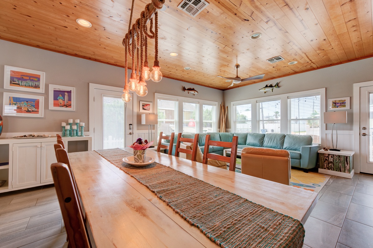 Gather around this beautiful wooden dining table where meals become memories under rustic rope lighting and warm coastal charm.