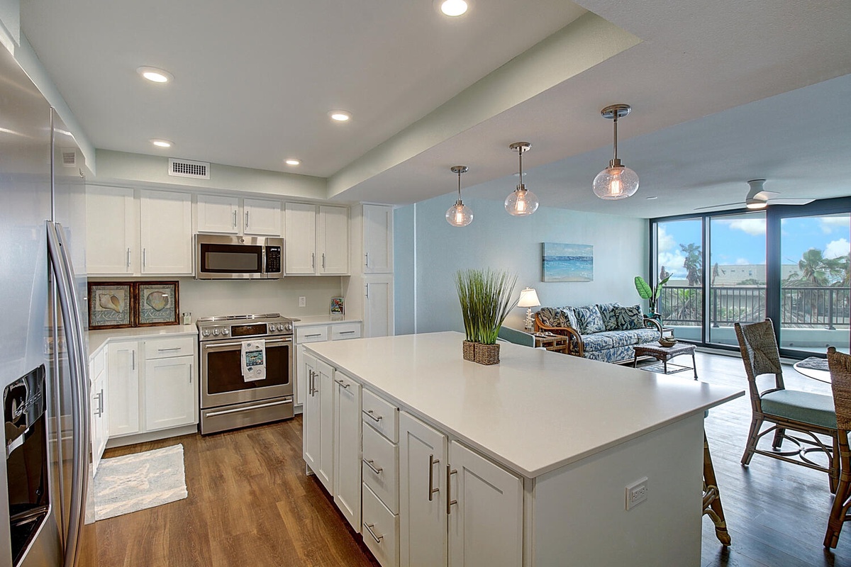 Your open-concept kitchen flows seamlessly into the living area, where modern white cabinets and sleek countertops create perfect spaces for cooking.