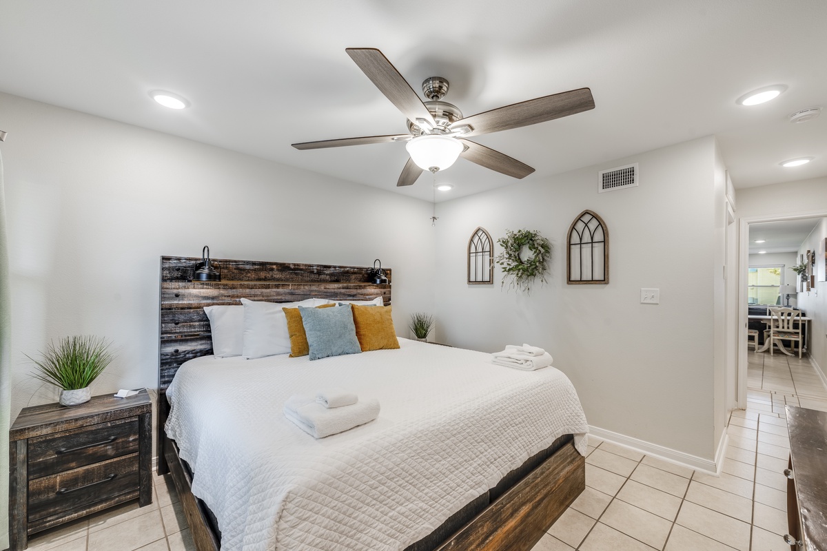 Rest peacefully in your modern bedroom with rustic wood furnishings, crisp linens, and a ceiling fan for ultimate comfort.
