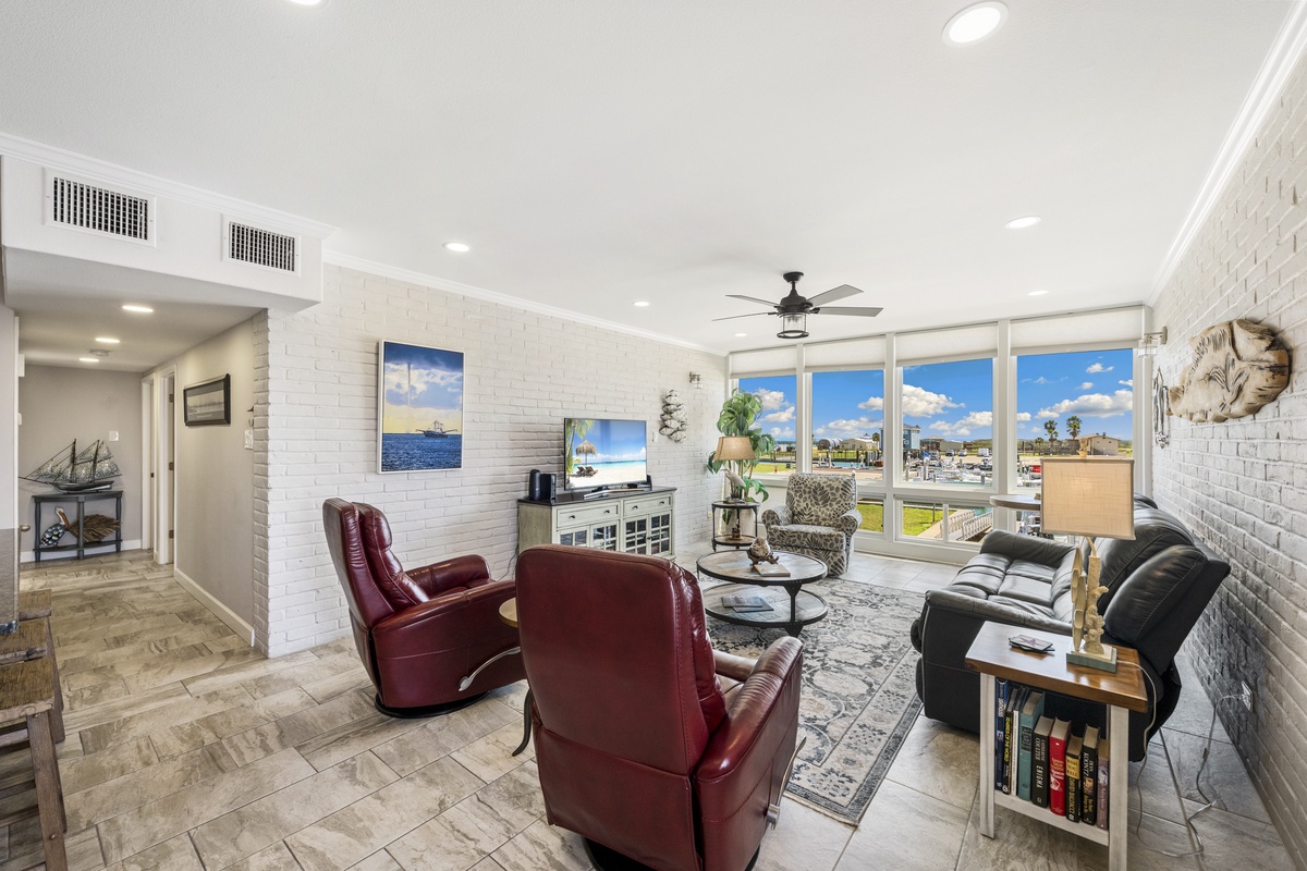 Relax in this bright living room with leather seating, exposed brick walls, and panoramic windows showcasing beautiful views.
