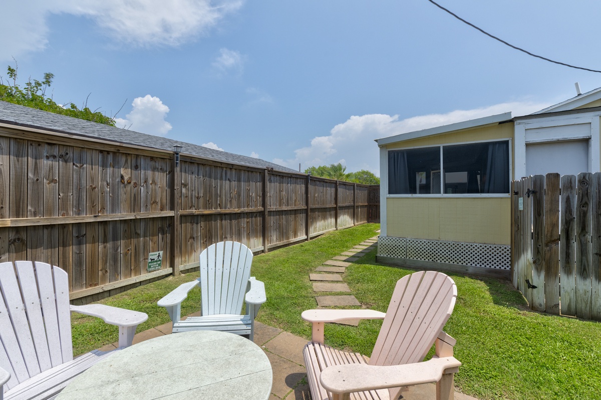 Your private backyard oasis features charming Adirondack chairs and a peaceful grassy area—perfect for unwinding with morning coffee or gathering for evening conversations under the open sky.
