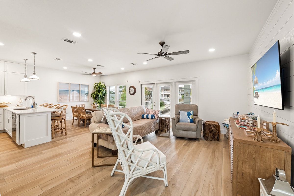 Settle into your open-concept living area, where coastal charm meets comfort. Plush seating, ceiling fans, and warm wood floors create a breezy, inviting atmosphere perfect for relaxing after a day of adventure.