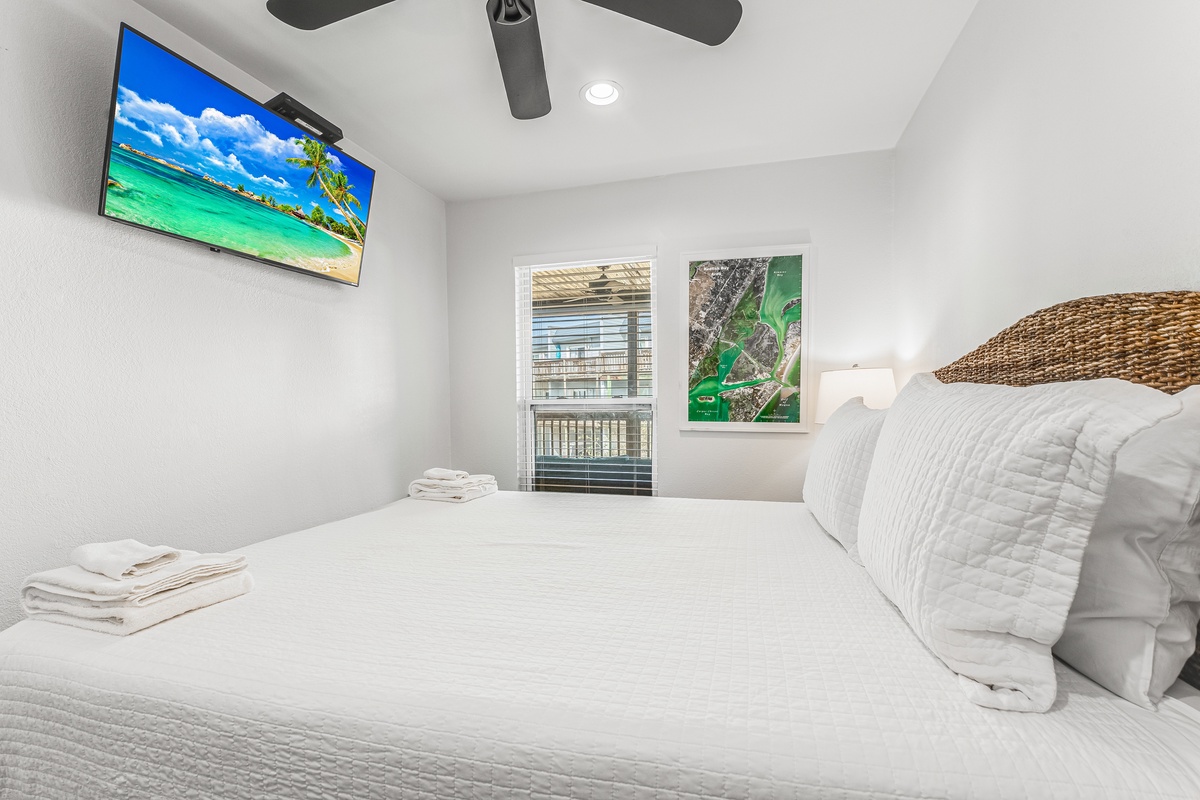 Sink into crisp white linens and tropical vibes with your wall-mounted TV and natural woven headboard creating the perfect beach getaway atmosphere.