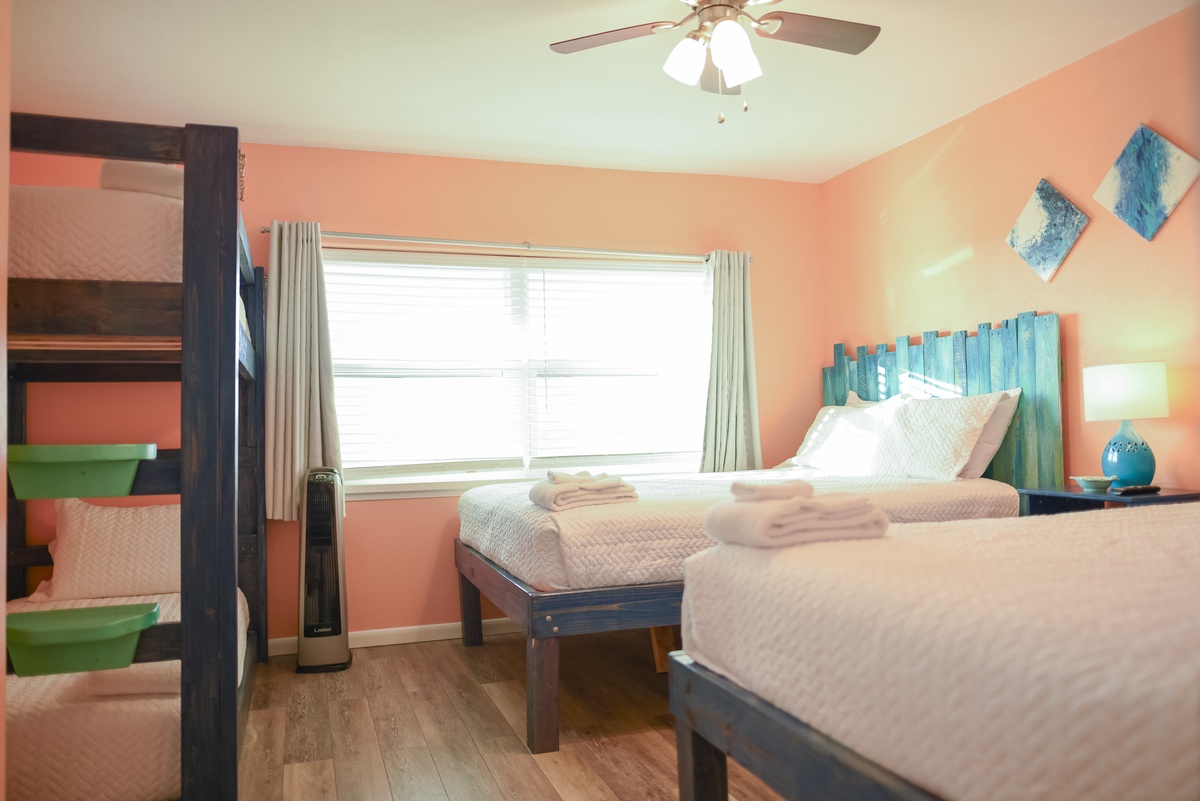 Wake up refreshed in this vibrant bedroom featuring twin beds, coastal-themed decor, and natural light streaming through your window.