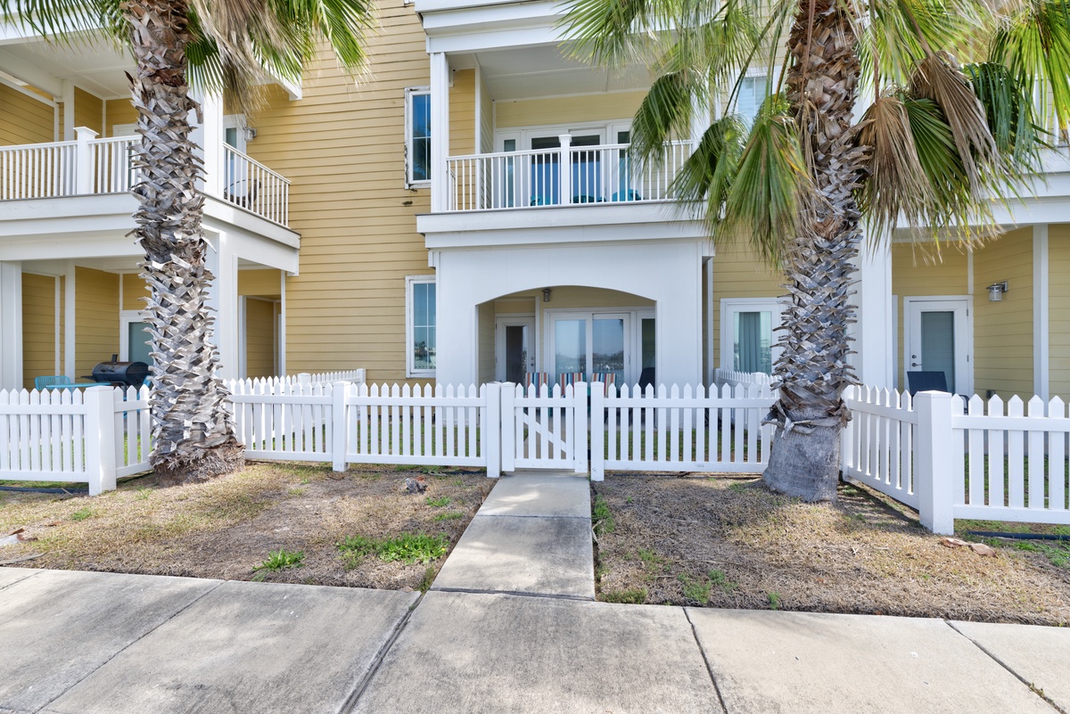 Coastal charm awaits at this sunny yellow townhome, complete with tropical palm trees and your own private fenced yard for relaxation.