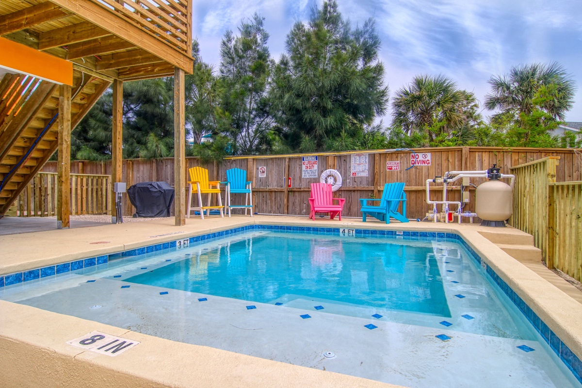 Your private pool oasis awaits with colorful Adirondack chairs and tropical palms creating the perfect backdrop for relaxation.