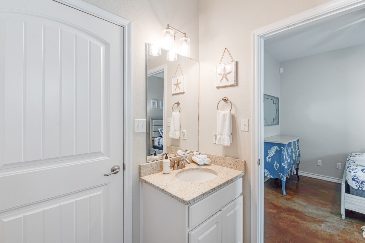 Step into your private vanity area with coastal charm—starfish art and crisp linens create a refreshing seaside retreat.