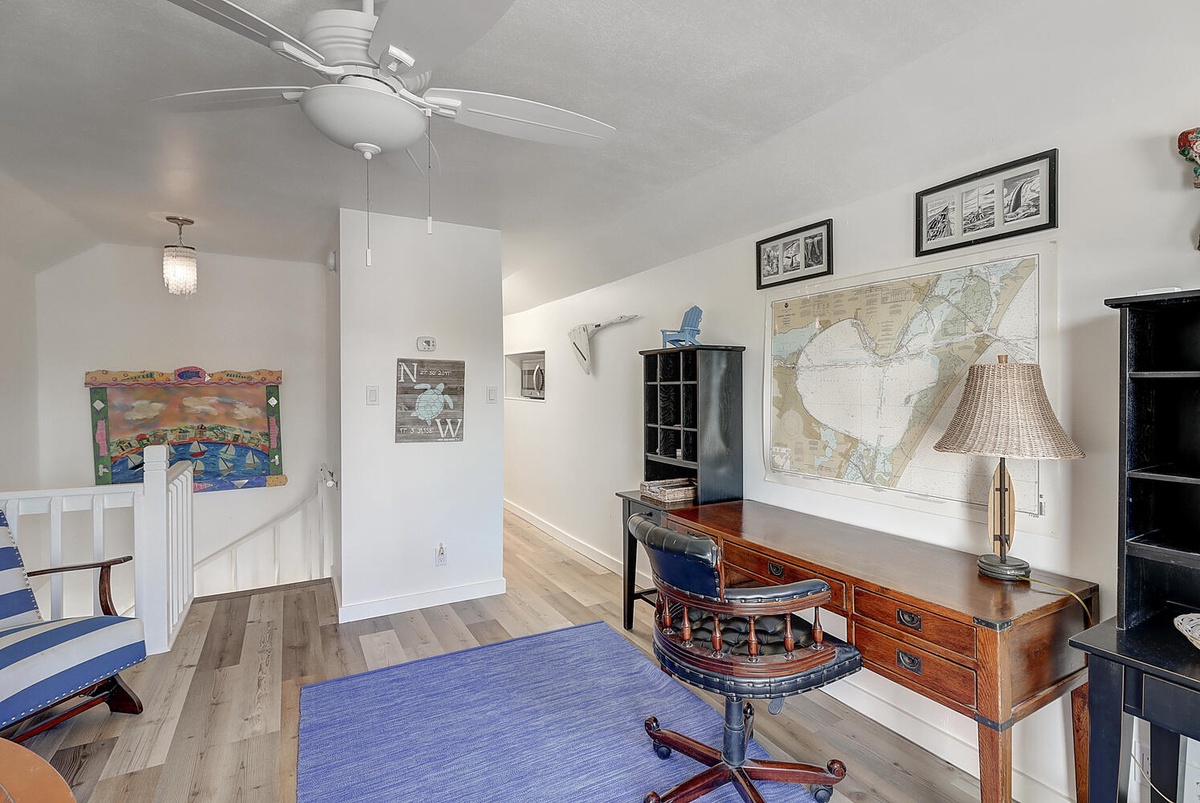 Your upstairs workspace awaits with nautical charm—vintage desk, local maps, and ocean breezes from the ceiling fan create the perfect retreat.
