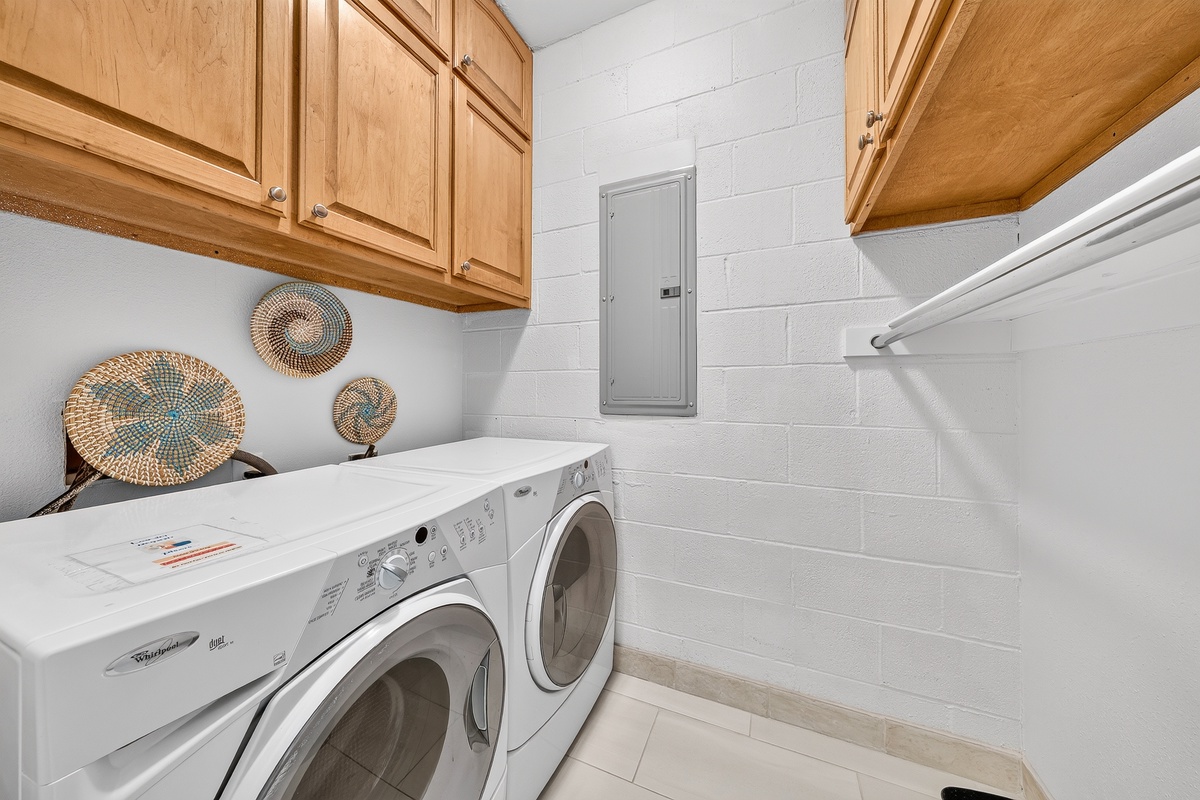 Your own private laundry space keeps everything running smoothly during your stay, with a full-size washer and dryer tucked beneath warm wood cabinetry and charming woven basket accents on the wall.