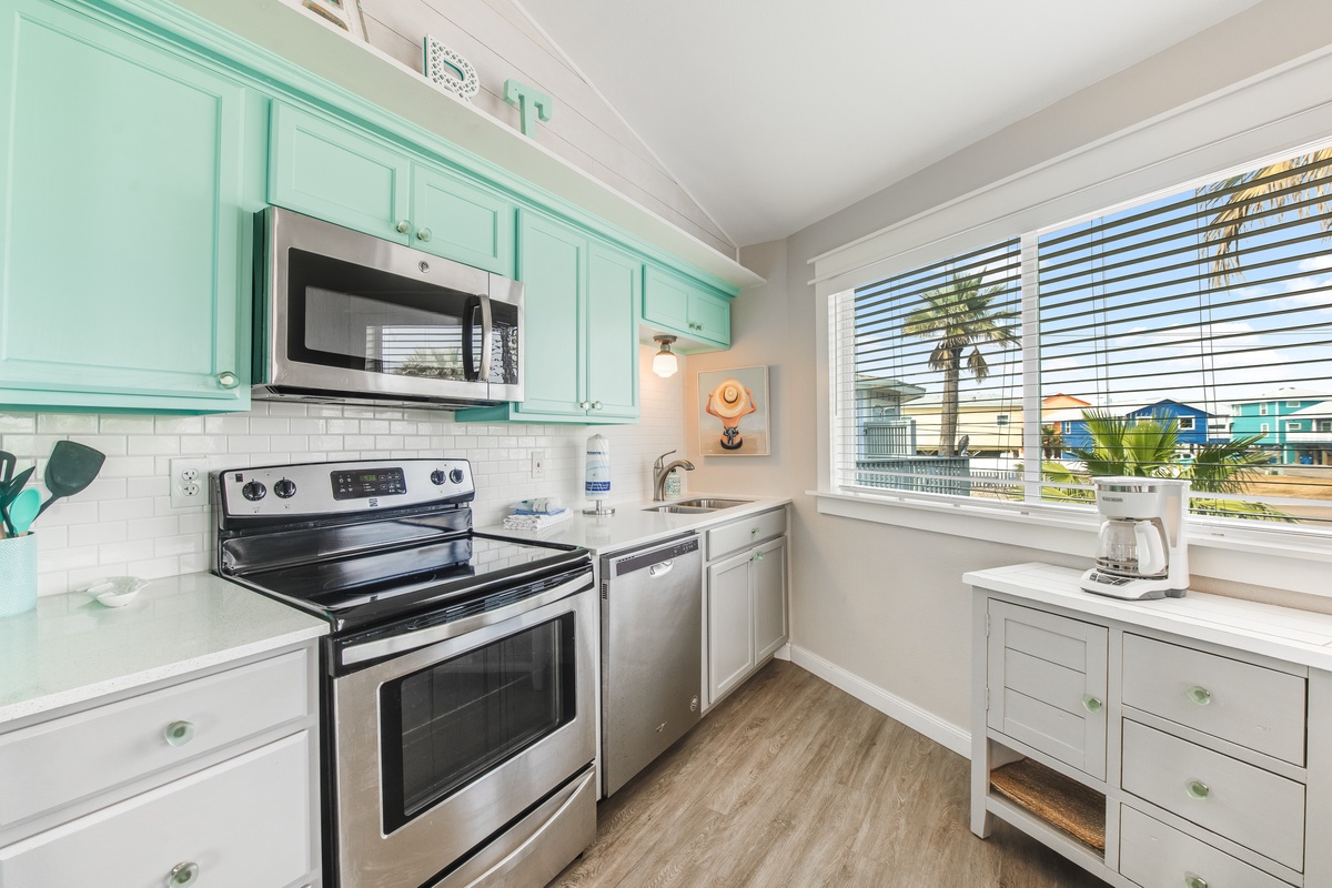 Your bright coastal kitchen offers modern appliances and charming mint-green cabinets, perfect for preparing meals while enjoying tropical views.